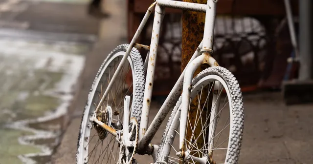 A white bicycle parked beside a New York City sidewalk.