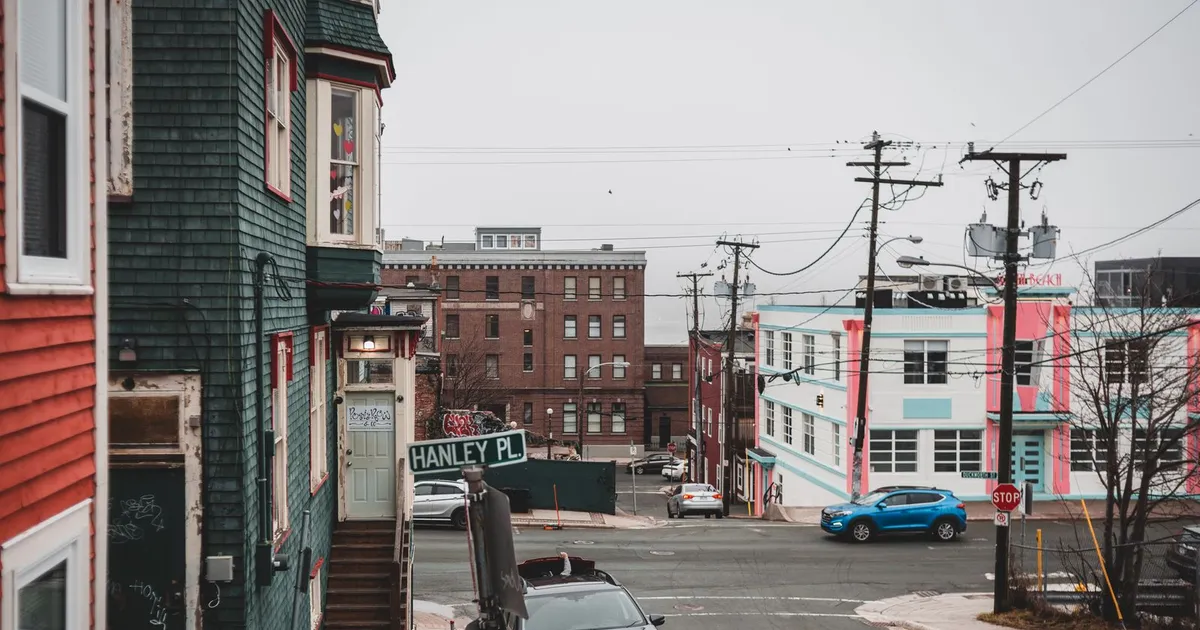 A residential street corner with buildings and cars.